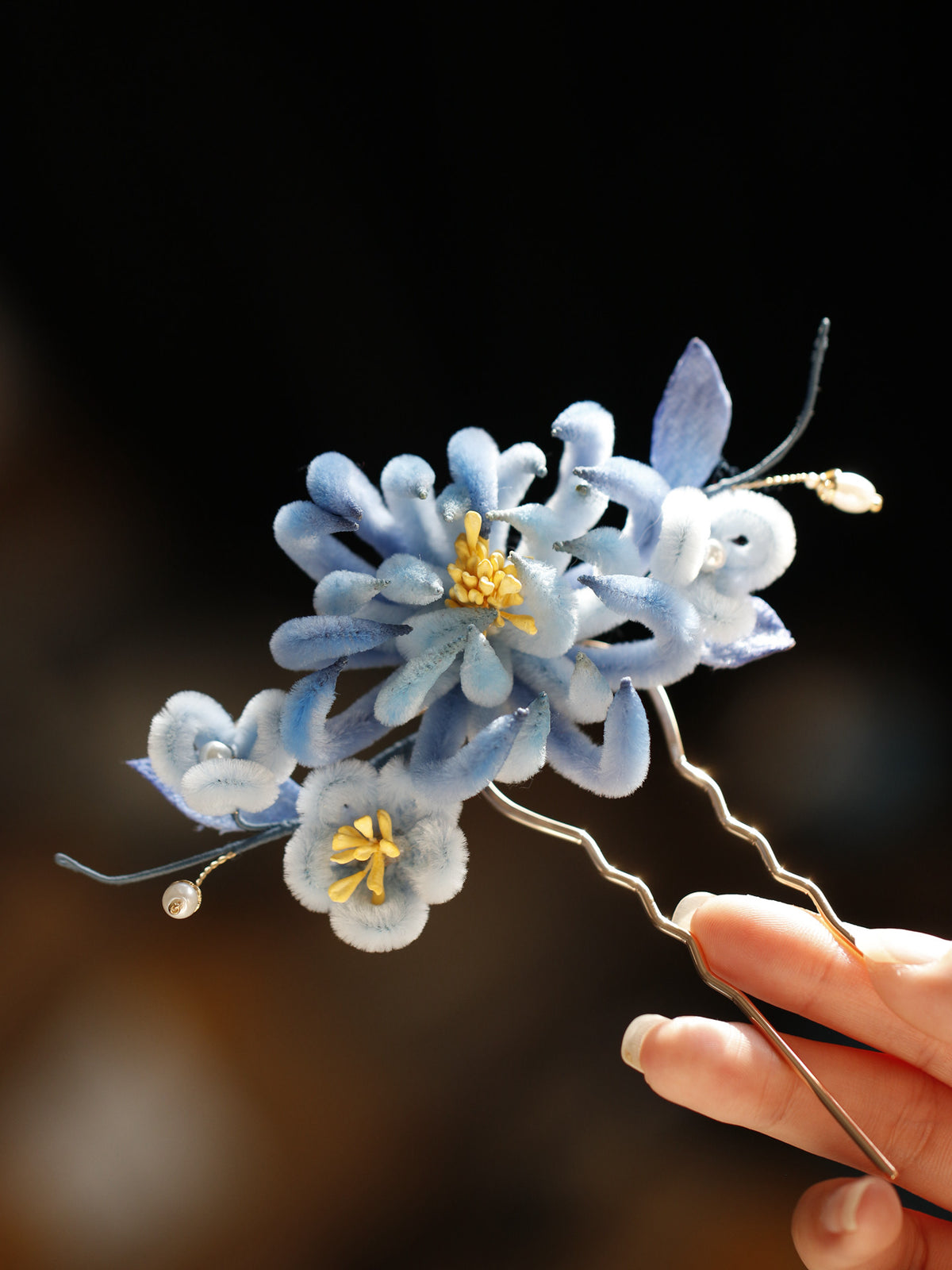 Blue chrysanthemum hairpin and decorative strands shown close up