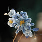 Blue floral hairpin held in hand to show its ornament