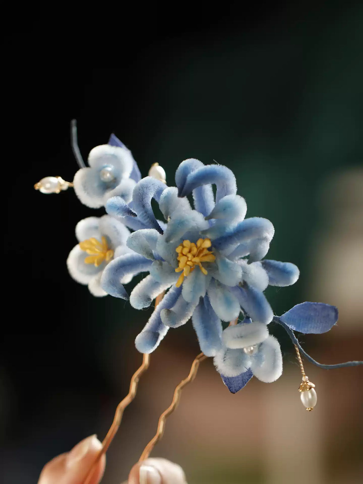 Blue floral hairpin held in hand to show its ornament