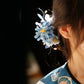Blue chrysanthemum ornament shown against dark hair