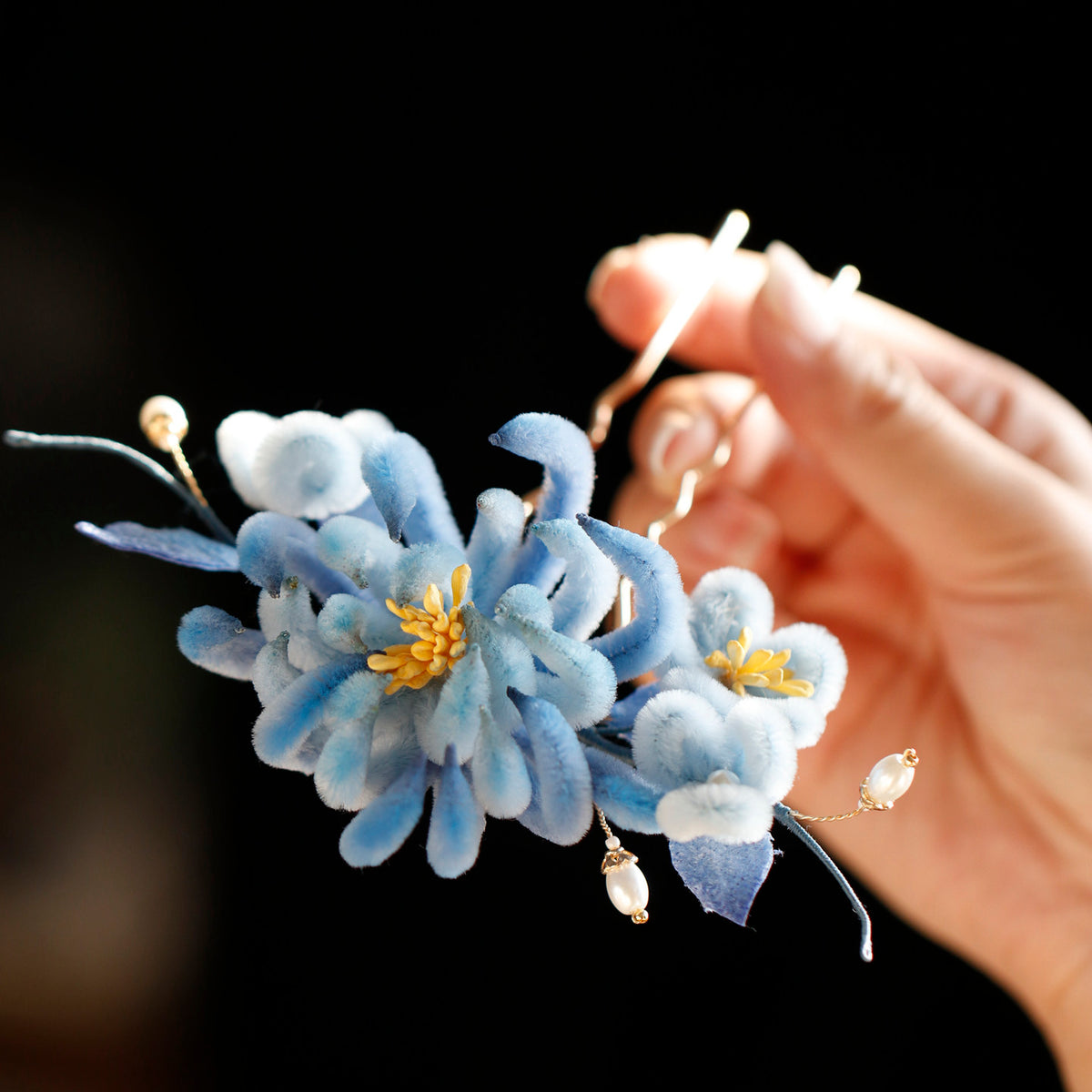 Hand-held closeup of the blue flower hairpin