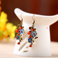 Blue cloisonne and red agate earrings on a white ceramic display stand