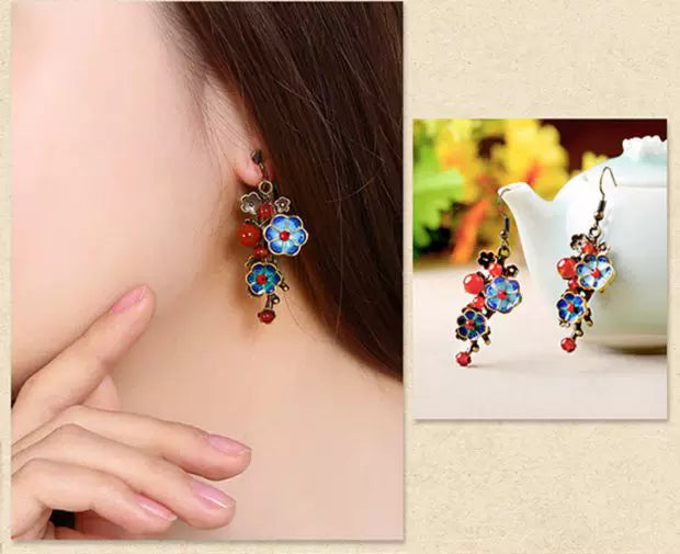 Two views of blue cloisonne earrings worn and displayed beside a teapot