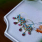 Pair of blue enamel flower drop earrings arranged in a white jewelry tray.