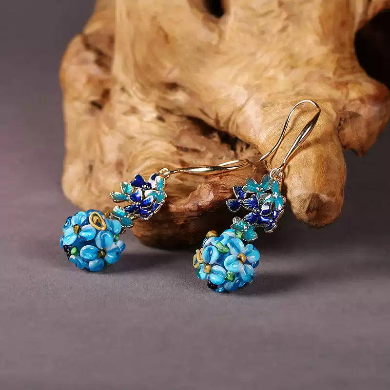 Blue floral drop earrings displayed against a wood-textured background