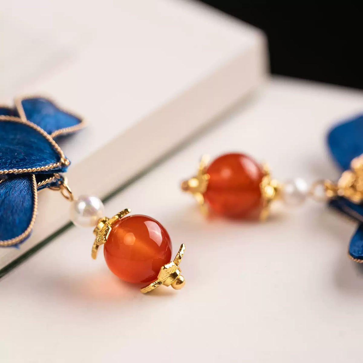 Detail of the red-orange and white bead accents on the blue flower earrings