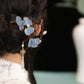 Blue ginkgo leaf hairpin worn in an updo with pearl tassel