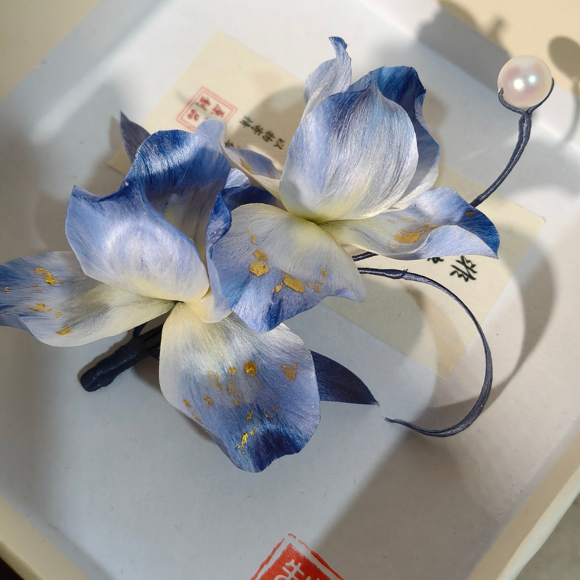 Close-up of handmade blue iris Ronghua petals with gold accents