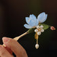 Detail view of the blue magnolia flower, green leaf, and dangling accents