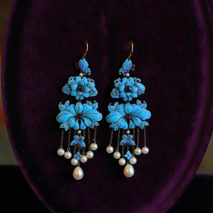 Pair of blue peony and butterfly drop earrings with pale bead tassels, shown on a jewelry bust