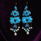 Front view of the blue floral and butterfly drop earrings with bead accents
