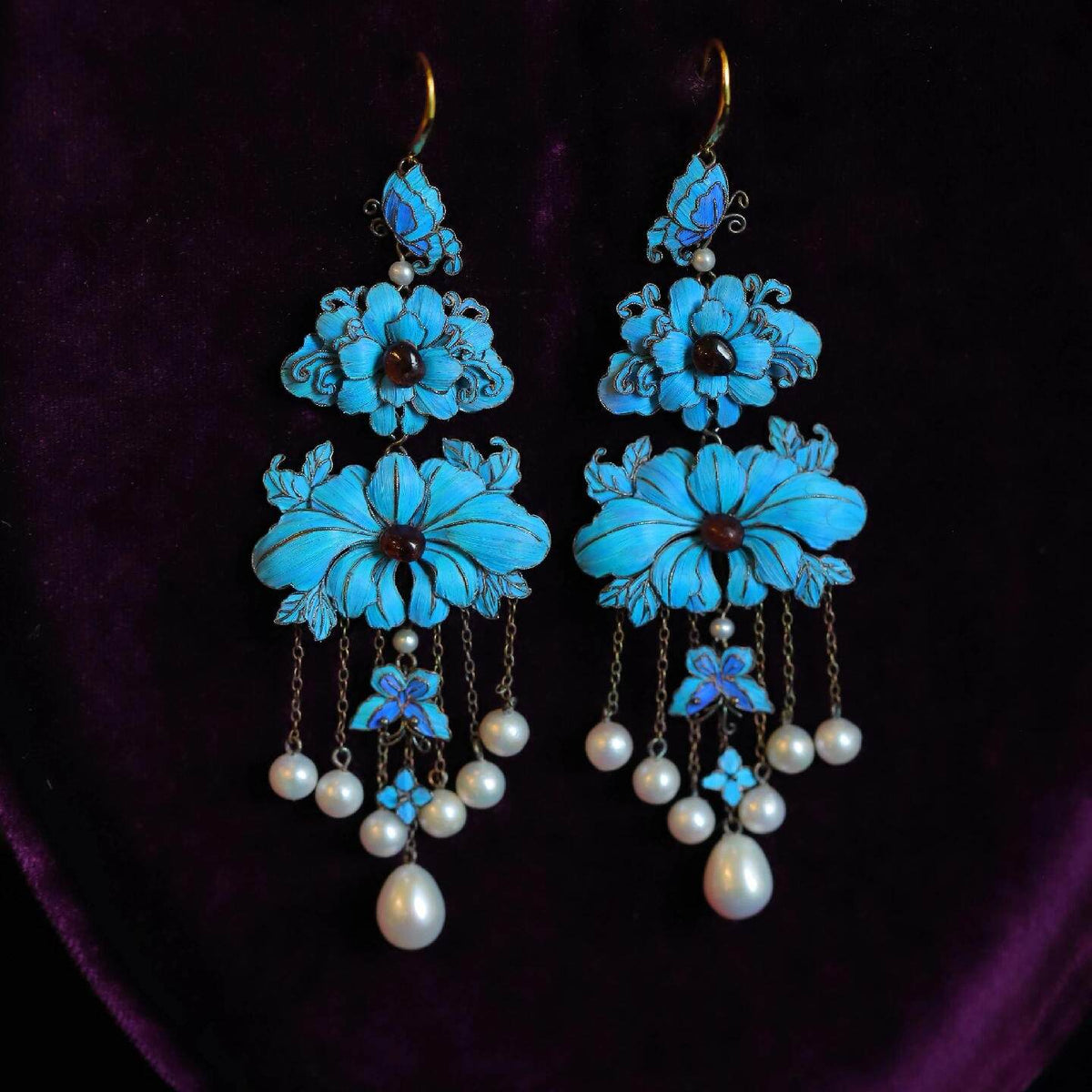 Front view of the blue floral and butterfly drop earrings with bead accents