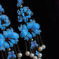 Detail view of the long blue floral earring drops and pale bead accents