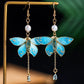 Close view of blue butterfly earrings showing pearl and teardrop details