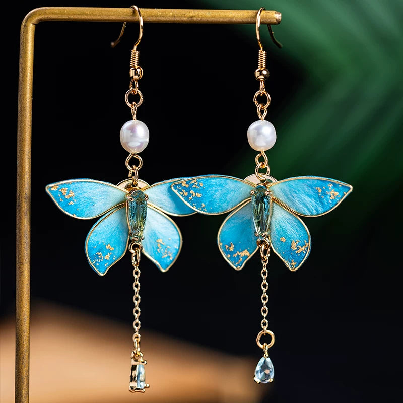 Close view of blue butterfly earrings showing pearl and teardrop details