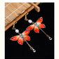 Close view of red butterfly earrings with pearl and chain-drop details