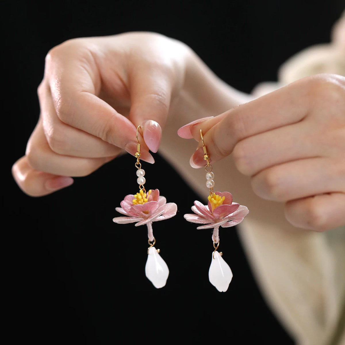 A pair of hand-wrapped lotus drop earrings shown in hand