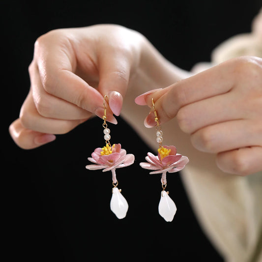 A pair of hand-wrapped lotus drop earrings shown in hand