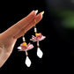 Pair of hand-wrapped lotus drop earrings in hand