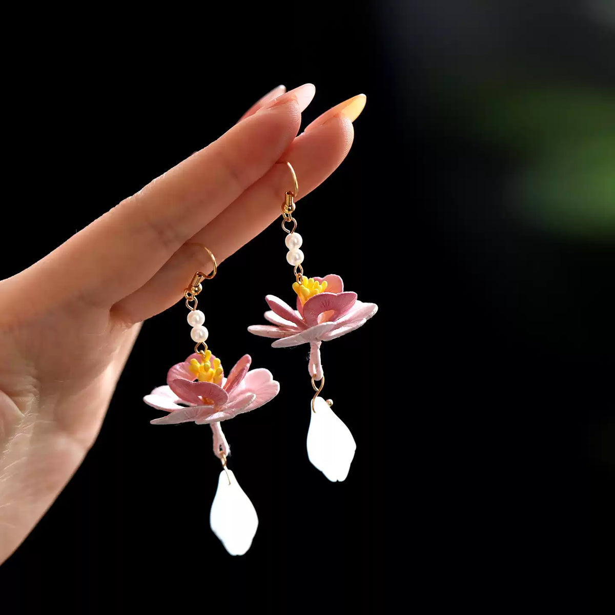 Pair of hand-wrapped lotus drop earrings in hand