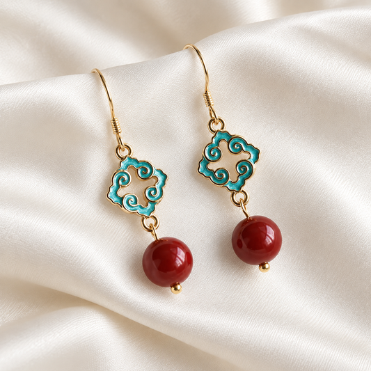 Turquoise and red bead drop earrings arranged on ivory silk