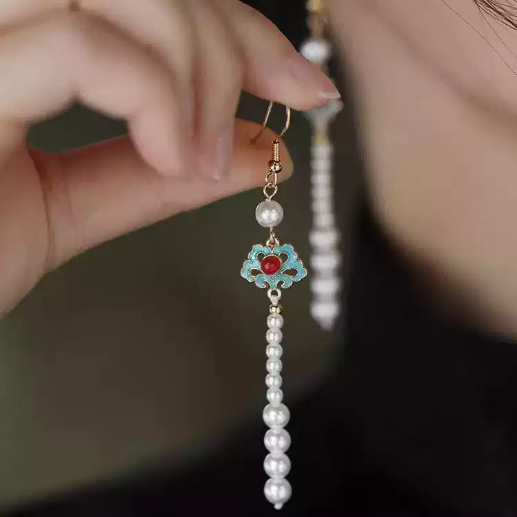 Close-up of the turquoise cloud-inspired earring with red center and white bead tassel
