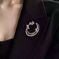Crescent moon and floral branch brooch worn on a black jacket