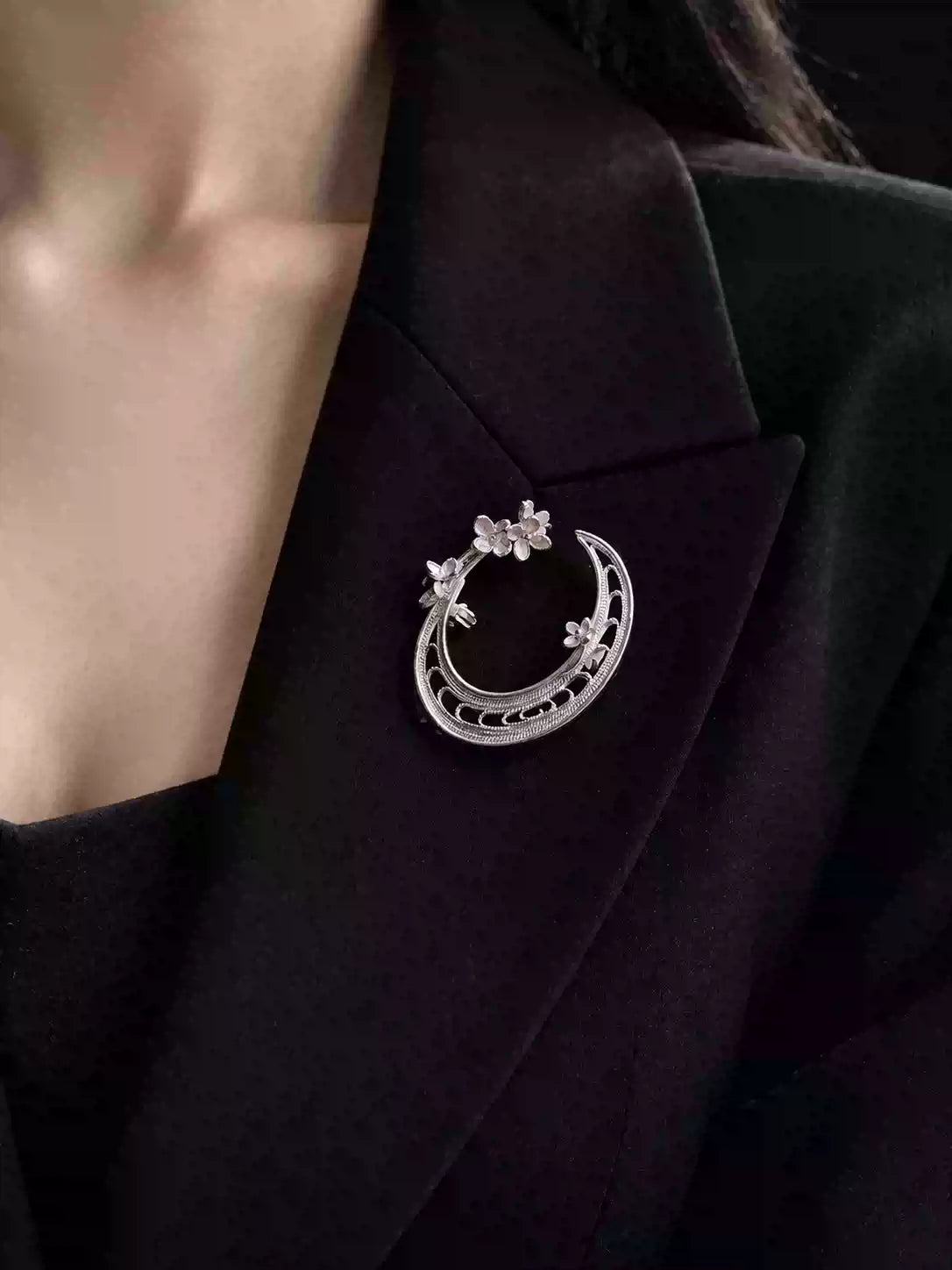 Crescent moon and floral branch brooch worn on a black jacket
