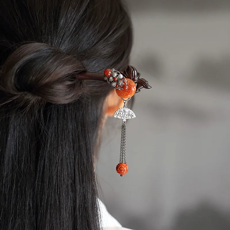 Red jadeite-style ornament and tassel on a red sandalwood hairpin worn in a bun