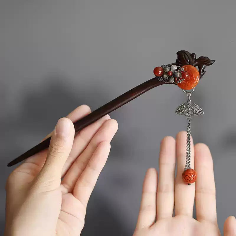 Close-up of the red carved accent and tassel on a red sandalwood hair stick