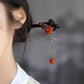 Side view of the red hairpin with a dangling tassel