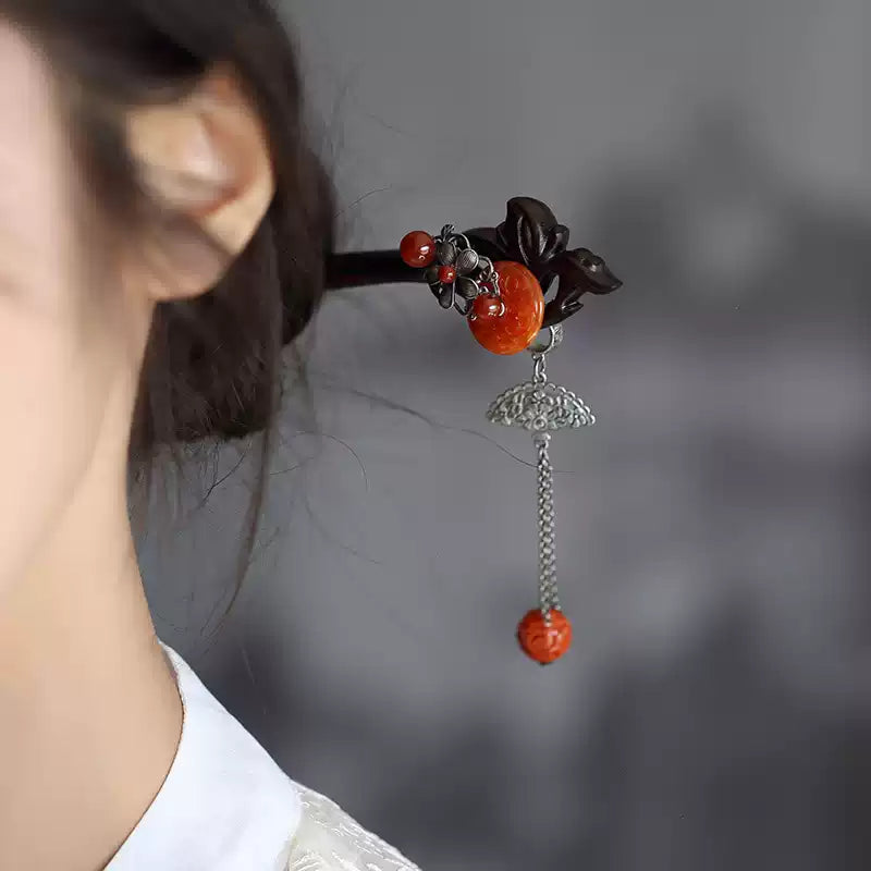 Side view of the red hairpin with a dangling tassel