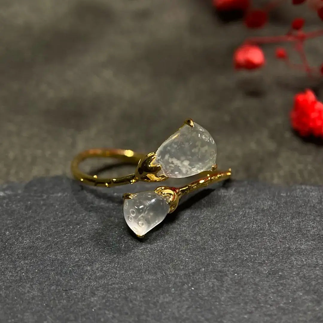 Front view of the adjustable gold-tone ring with two lotus pod accents