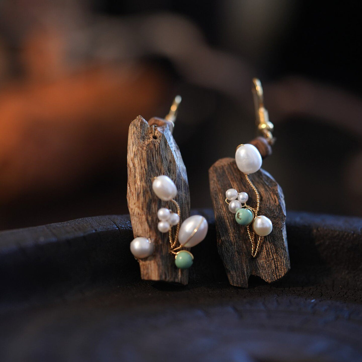 Detail of the irregular earrings showing pearl accents and a pale green bead.