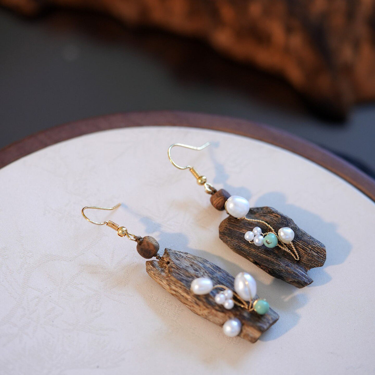 Close view of the pair of irregular drop earrings with pearl accents.