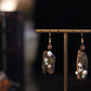 Pair of irregular faux agarwood-style earrings with pearl accents, shown hanging.