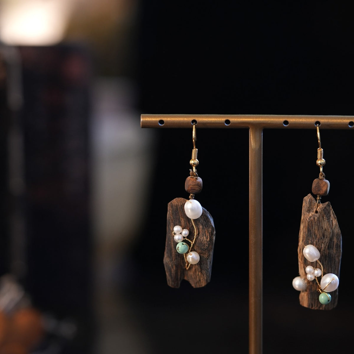 Pair of irregular faux agarwood-style earrings with pearl accents, shown hanging.