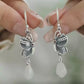 Close-up of the matching butterfly drop earrings held against a neutral background