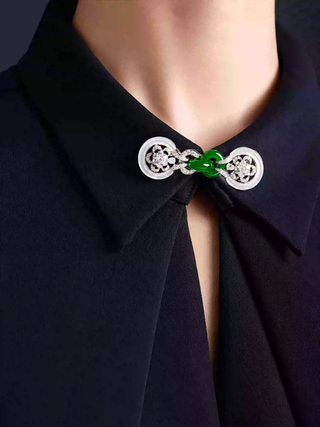 Faux-jade Chinese-style collar brooch worn at the neckline of a dark blouse