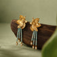 Pair of floral stud earrings displayed on a dark wood stand