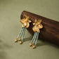 Angled view showing the flower relief, pale green beads, and dangling accents