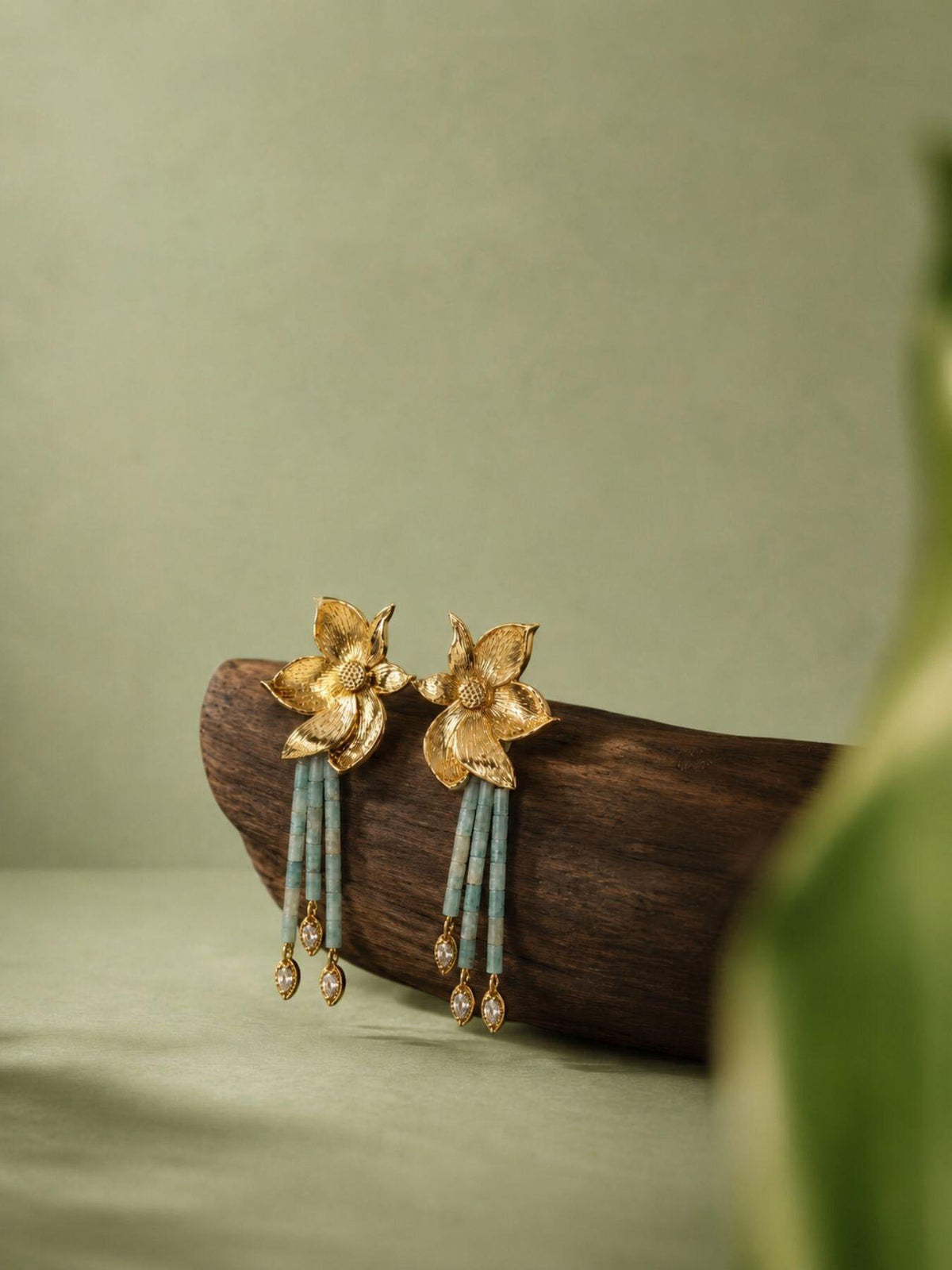 Pair of gold-tone flower earrings with pale green bead strands and dangling clear accents