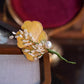 Close view of the pale yellow petals and white details on the ginkgo leaf brooch