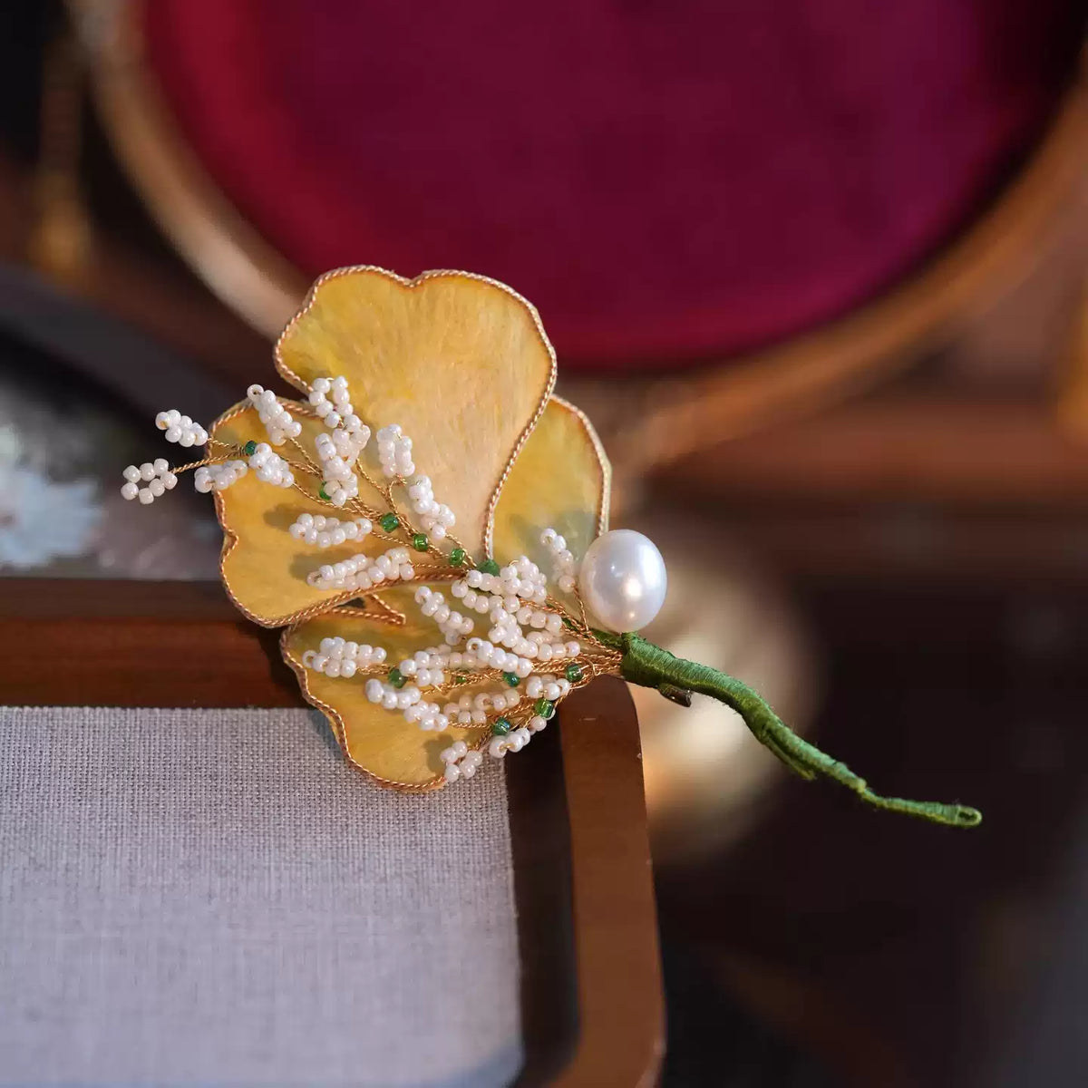 Close view of the pale yellow petals and white details on the ginkgo leaf brooch