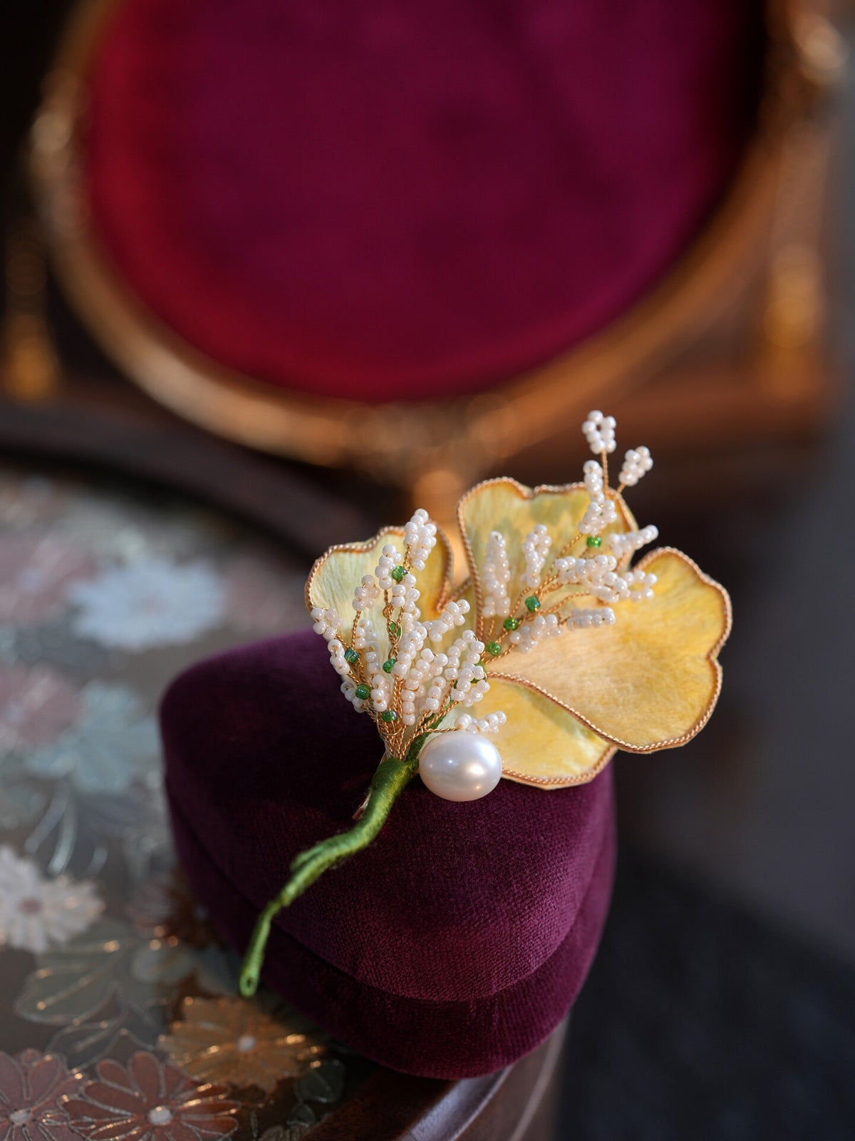 Front view of a ginkgo leaf floral brooch with pale yellow petals, white accents, green details, and gold-tone branches