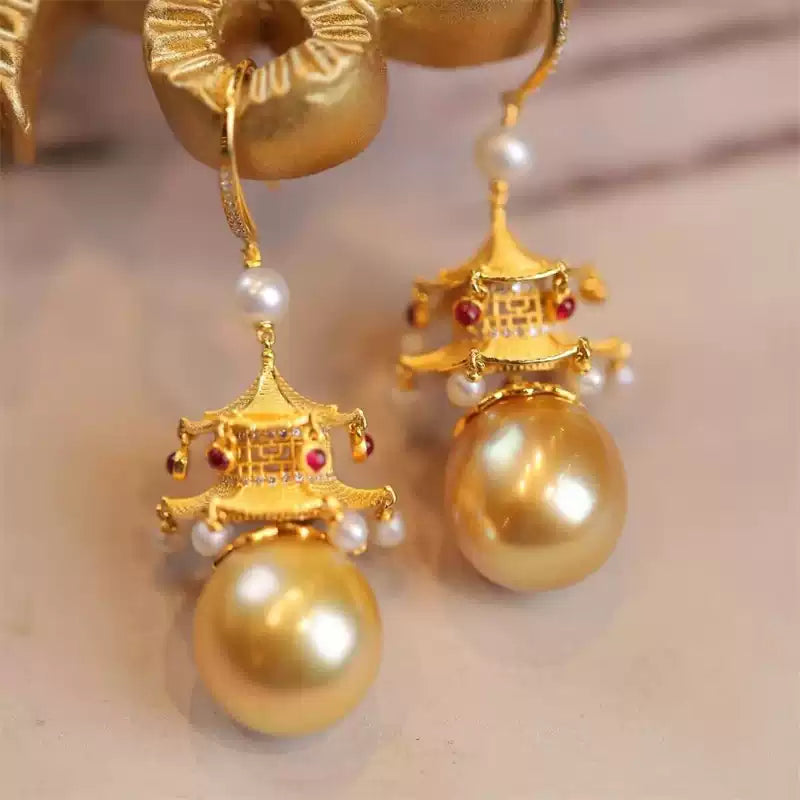 Detail of gold-tone architectural drop earrings with pearl-like beads