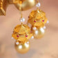 Close-up of pavilion-shaped earring drops with imitation pearl accents