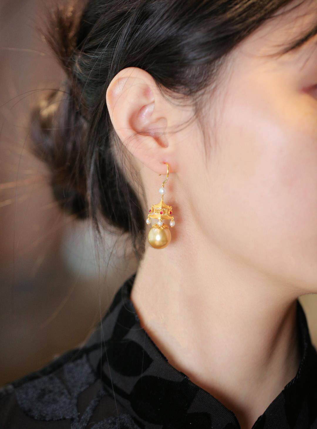 Side view of a pavilion and imitation pearl drop earring worn on the ear