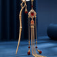 Full view of gold bamboo tassel hairpin on navy background