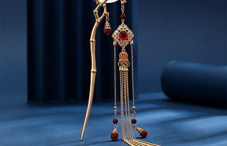 Full view of gold bamboo tassel hairpin on navy background